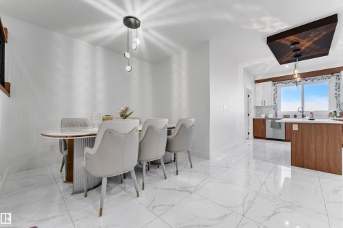 White marble-look tile flooring throughout, with a contemporary pendant light fixture over the dining area - 6502 42 Ave, Beaumont, AB 