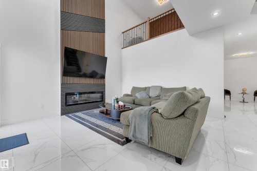 High ceilings with recessed lighting, a modern linear fireplace, and a decorative slatted wall accent - 6502 42 Ave, Beaumont, AB 