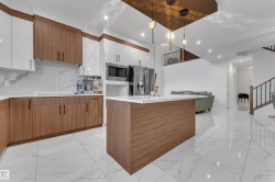 Kitchen featuring wood-finish cabinetry, white upper cabinets, stainless steel appliances, and a central island with a white countertop - 