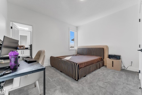 Recessed lighting, light-toned carpeting, a window with exterior scenery, a white interior door with black hardware, and a white wall finish - 6502 42 Ave, Beaumont, AB 