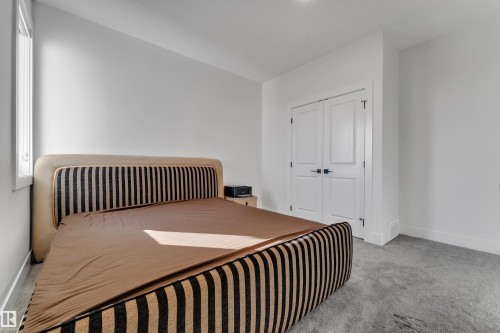 Window with white trim, light gray carpet, and white double doors - 6502 42 Ave, Beaumont, AB 