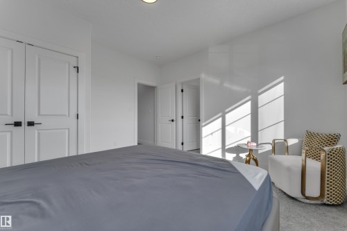 White walls, white doors with modern black hardware, and light carpet flooring - 6502 42 Ave, Beaumont, AB 