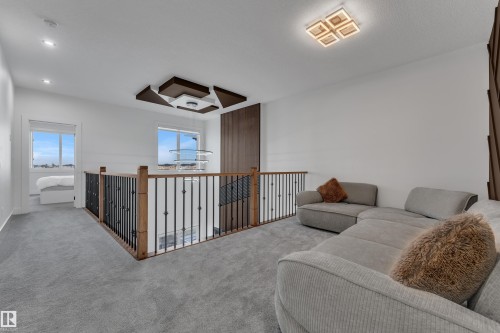 Open landing featuring carpet flooring and a wood and wrought iron railing - 6502 42 Ave, Beaumont, AB 
