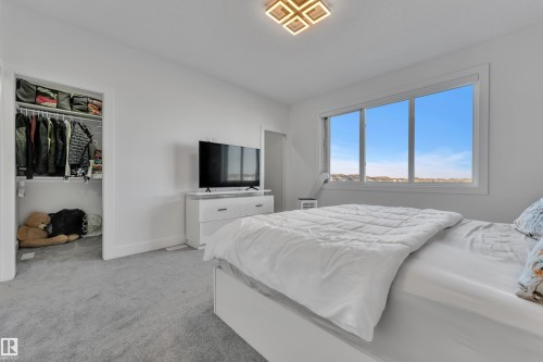 Spacious room featuring light gray carpet flooring, large multi-pane window, and a built-in closet with shelving and hanging storage - 6502 42 Ave, Beaumont, AB 
