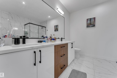 Dual vanity with white cabinetry, wood-finish drawers, and black hardware - 6502 42 Ave, Beaumont, AB 