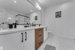 Dual vanity with white cabinetry, wood-finish drawers, and black hardware - 