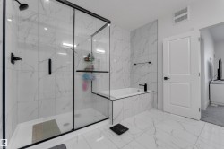 Walk-in shower with clear glass enclosure and black frame - 