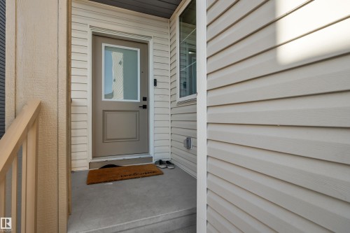 Entryway featuring a panel door with frosted glass, matte black hardware, and concrete steps - 6502 42 Ave, Beaumont, AB 