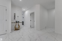 White tile flooring with veining, white walls, recessed lighting, and white interior doors with dark hardware - 