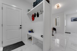Mudroom with built-in bench seating, integrated storage, white panel doors, and tile flooring - 