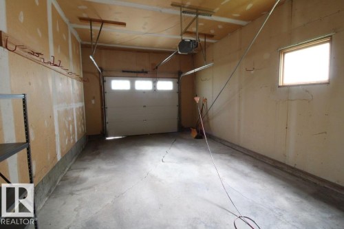 Single garage door with upper window panels, concrete flooring, and a single window - 44 Arlington Drive, St. Albert, AB 