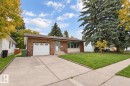 Brick exterior with stone accents, attached garage, concrete driveway, and front lawn - 44 Arlington Drive, St. Albert, AB 
