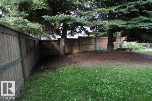 Expansive green space featuring established mature trees and a wood panel fence - 44 Arlington Drive, St. Albert, AB 