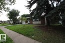Brick and stone facade with large windows, mature trees, and a concrete pathway - 44 Arlington Drive, St. Albert, AB 