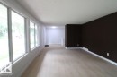 Light wood-finish flooring, multiple large windows with white trim, and a contrasting accent wall - 44 Arlington Drive, St. Albert, AB 