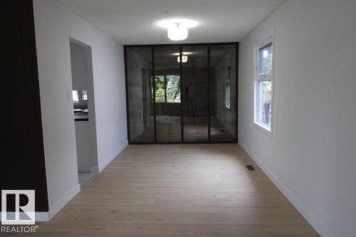 Light wood-finish flooring, white painted walls, and a multi-paneled glass partition - 44 Arlington Drive, St. Albert, AB 