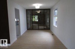 Light wood-finish flooring, white painted walls, and a multi-paneled glass partition - 