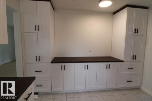 White shaker-style cabinetry with dark wood-finish countertops, tile flooring, and integrated overhead lighting - 44 Arlington Drive, St. Albert, AB 