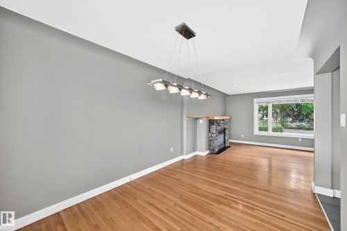 Hardwood flooring and a stone-clad fireplace with a wood mantel - 10715 133 Street Nw, Edmonton, AB 