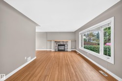 Hardwood flooring, stone-clad fireplace with wood mantel, large bay window, and neutral wall tones - 