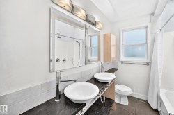 Double vessel sinks with chrome fixtures, large mirror, and tiled walls - 
