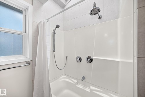 Bathtub shower combination with tiled surround, handheld shower, and chrome fixtures - 10715 133 Street Nw, Edmonton, AB 