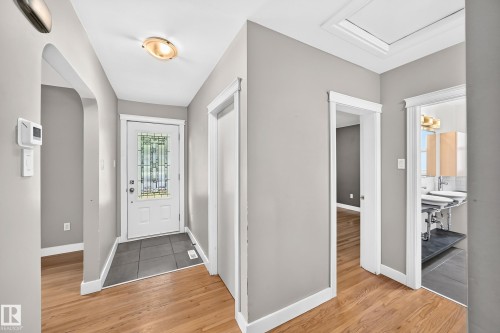 Entryway featuring a decorative glass front door, large format tile flooring, and wood-finish flooring - 10715 133 Street Nw, Edmonton, AB 