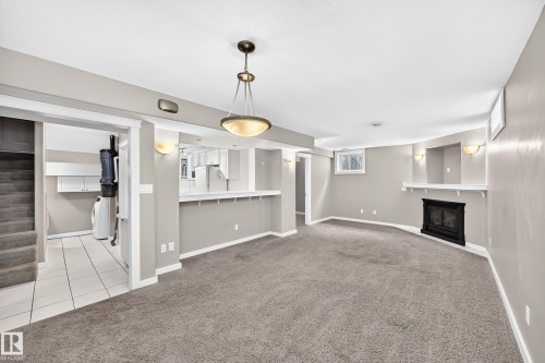 Spacious living area with wall-to-wall carpeting, a built-in fireplace, and a large pass-through window - 10715 133 Street Nw, Edmonton, AB 