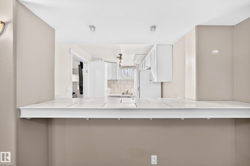 Kitchen pass-through with a tiled countertop and decorative trim - 10715 133 Street Nw, Edmonton, AB 