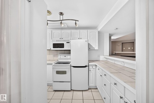 White kitchen cabinetry with track lighting and an integrated microwave - 10715 133 Street Nw, Edmonton, AB 