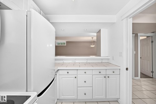 White cabinetry with brushed nickel hardware, tile countertop, and matching tile flooring - 10715 133 Street Nw, Edmonton, AB 
