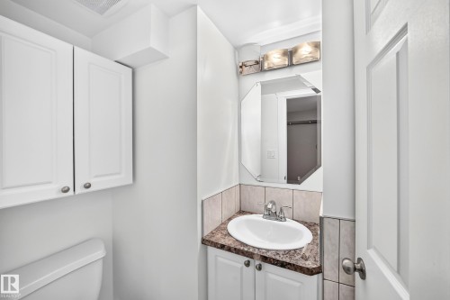 White cabinetry, corner vanity with integrated sink, chrome faucet, and rectangular mirror - 10715 133 Street Nw, Edmonton, AB 