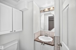 White cabinetry, corner vanity with integrated sink, chrome faucet, and rectangular mirror - 