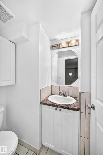 White vanity with cabinet storage, brown-flecked countertop, and an oval undermount sink - 10715 133 Street Nw, Edmonton, AB 