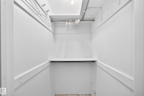 White-painted walls with upper and lower hanging rods, a single shelf, and ceiling-mounted lighting - 10715 133 Street Nw, Edmonton, AB 