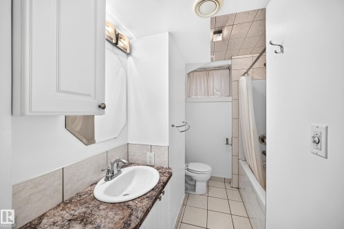 Vanity with a polished chrome faucet, stone-finish countertop, and white cabinetry - 10715 133 Street Nw, Edmonton, AB 