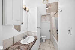 Vanity with a polished chrome faucet, stone-finish countertop, and white cabinetry - 