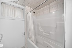 White tiled bathroom with a window, built-in tub, and tiled wall accents - 