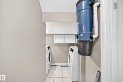 Laundry area with a built-in central vacuum system, tile flooring, and white cabinetry - 