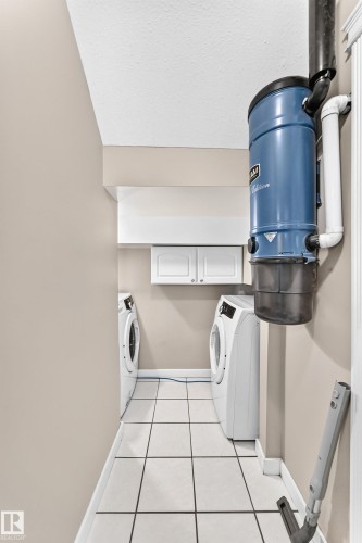 Utility area featuring white square tile flooring, a wall-mounted central vacuum system, and built-in white cabinetry - 10715 133 Street Nw, Edmonton, AB 