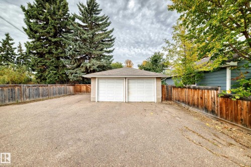 Detached two-car garage with white paneled doors, accompanied by a spacious paved driveway - 10715 133 Street Nw, Edmonton, AB 