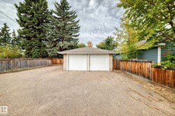 Detached two-car garage with white paneled doors, accompanied by a spacious paved driveway - 