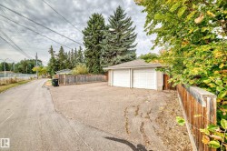Detached two-car garage with two white garage doors, asphalt shingle roof, and wood fencing - 