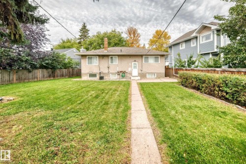 Expansive backyard featuring a concrete pathway, mature perimeter landscaping, and a wood privacy fence - 10715 133 Street Nw, Edmonton, AB 