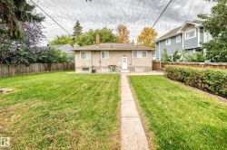 Expansive backyard featuring a concrete pathway, mature perimeter landscaping, and a wood privacy fence - 