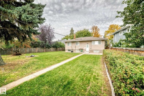Expansive backyard featuring a manicured lawn, established perimeter fencing, and mature trees - 10715 133 Street Nw, Edmonton, AB 