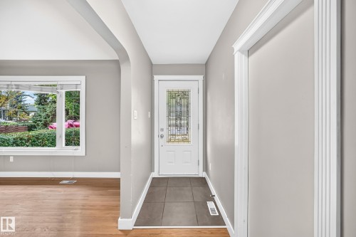 Entryway featuring a white door with a leaded glass insert, dark tile flooring, and light gray walls - 10715 133 Street Nw, Edmonton, AB 