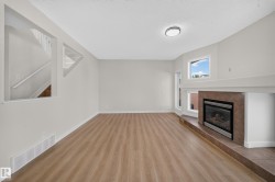 Expansive living area featuring wood-finish flooring and a tiled fireplace - 