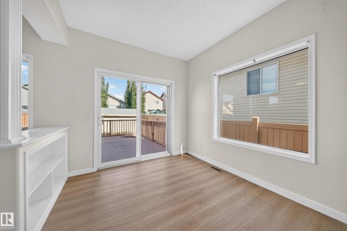 Wood-finish flooring, built-in shelving, large picture window, and sliding glass door leading to a wood deck - 7836 7 Ave Sw Sw, Edmonton, AB 