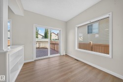 Wood-finish flooring, built-in shelving, large picture window, and sliding glass door leading to a wood deck - 